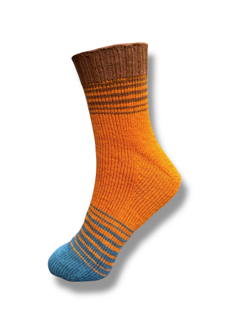Sneaker & Socken Fade mit Monkferse Strickanleitung (Toe up) in lebendigem Orange mit Akzenten in Braun und Blau, gestrickt aus Modal Farbverlaufsgarn aus natürlichen Fasern – Modal Farbverlaufsgarn zum Verlieben.